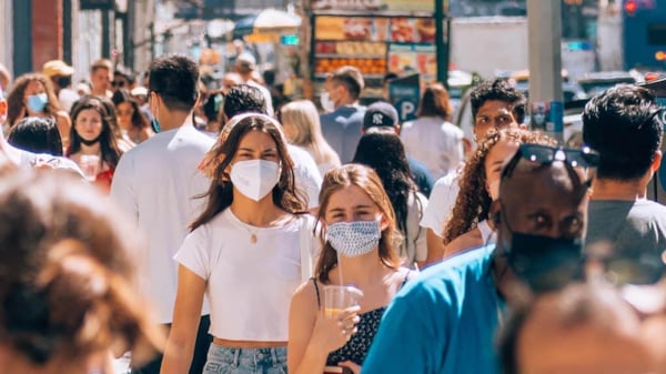 People wearing masks walking down a busy street